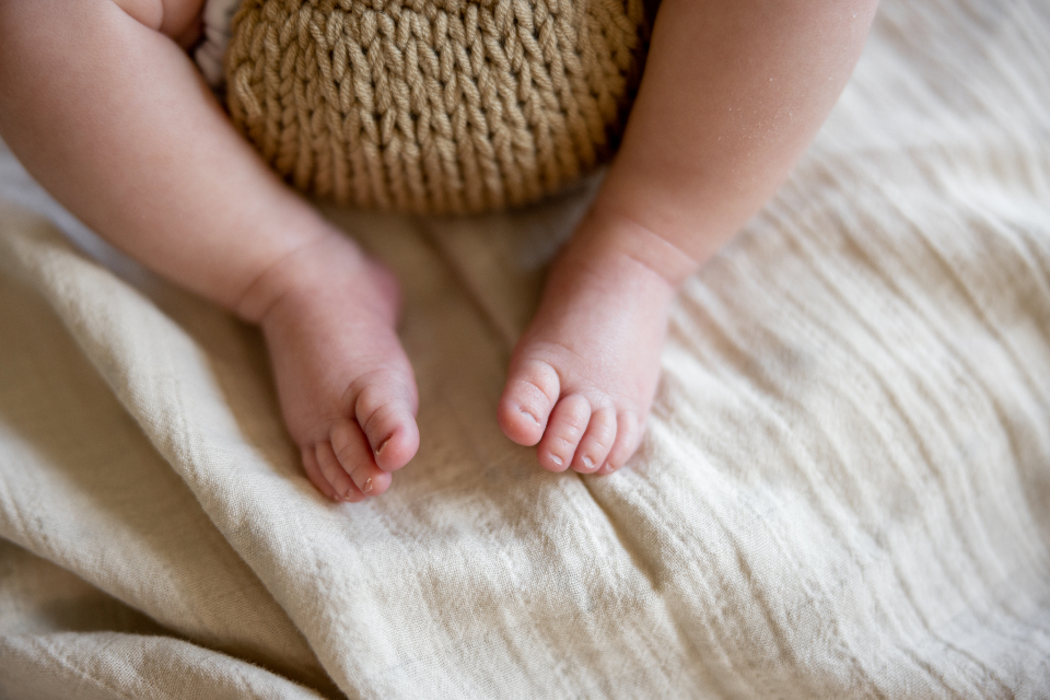 Tiny baby feet resting on a soft linen blanket